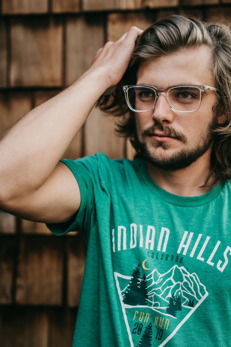 Man In Teal Shirt Wearing Eyeglasses Fixing His Hair 