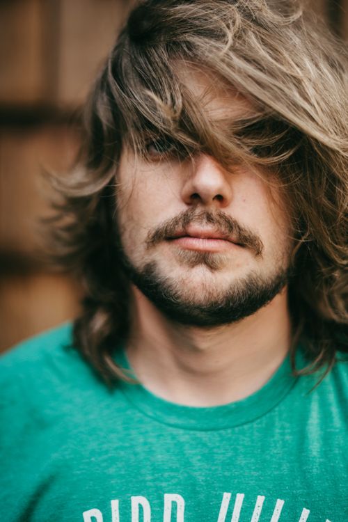 Free A close-up portrait of a bearded man wearing a green shirt with text, showcasing a relaxed expression. Stock Photo
