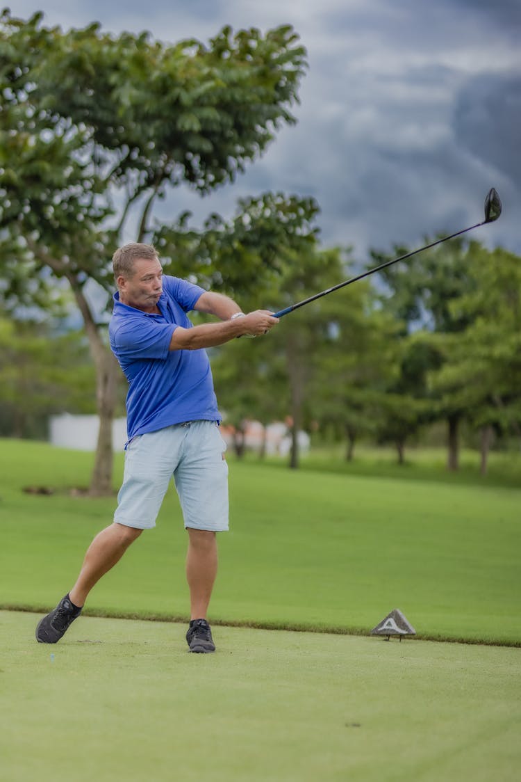 A Man In Blue Polo Shirt Playing Golf