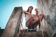 一位年轻女子在城市屋顶的梯子上摆出时尚的姿势