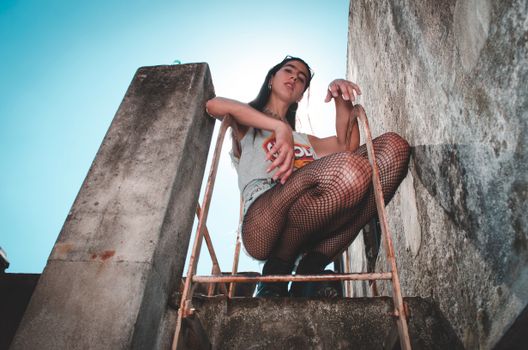 一位年轻女子在城市屋顶的梯子上摆出时尚的姿势