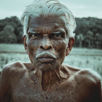 Close-up portrait of an elderly man with a strong expression against a natural background.