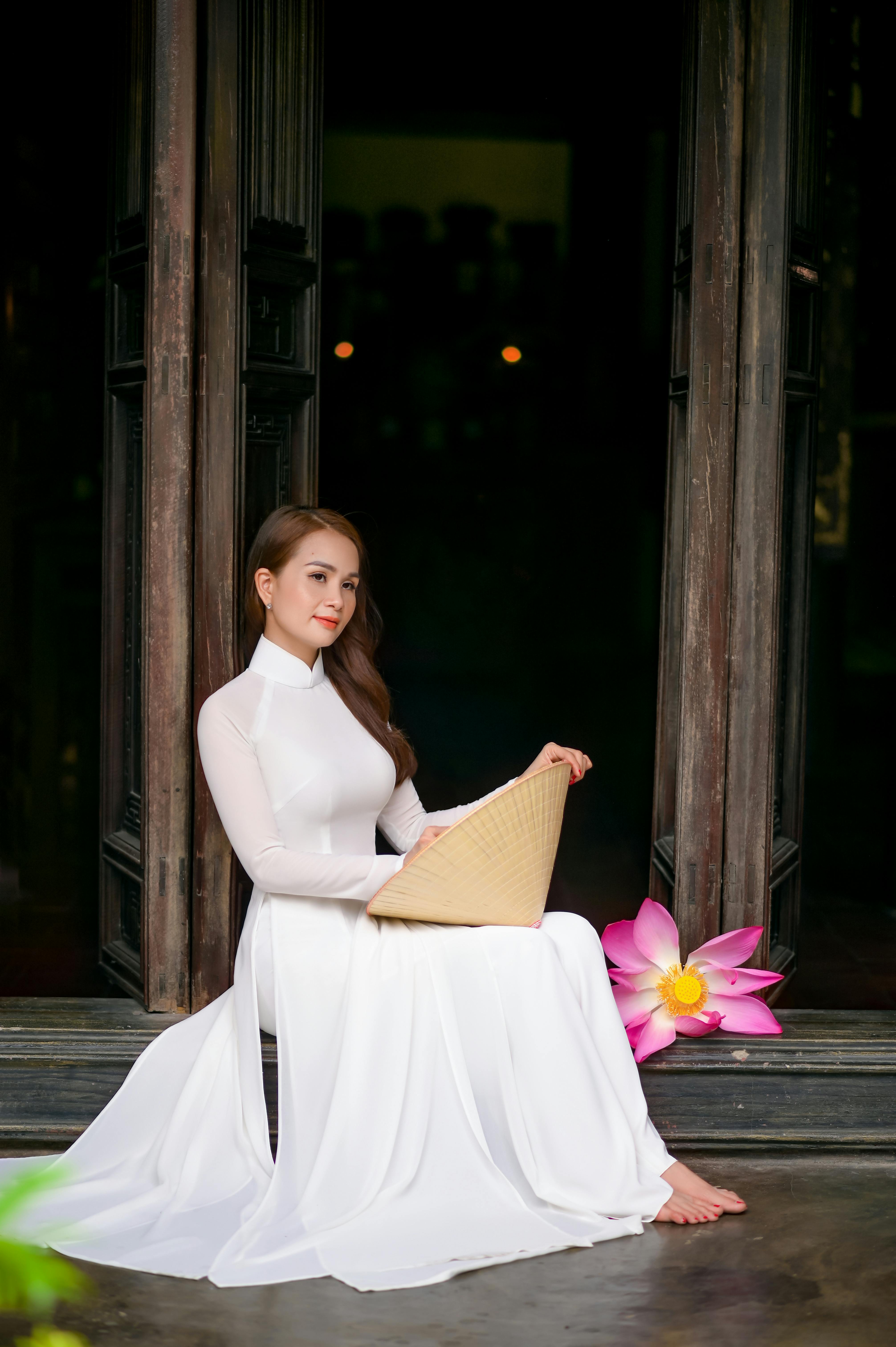 woman in white dress holding a conical hat