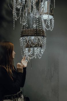 Woman in black long sleeves admiring elegant hanging chandeliers indoors.
