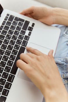 Hands typing on a laptop keyboard in a high angle vertical shot.