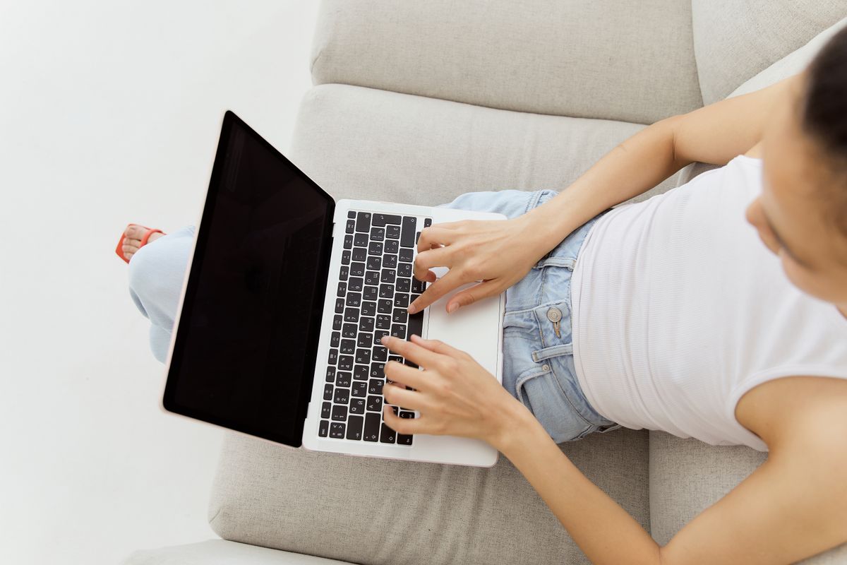 Masa başında dizüstü bilgisayarla online platforma kayıt olan genç kullanıcı