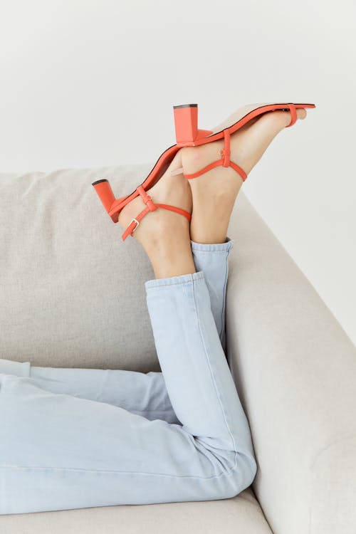 Free Woman in Orange Leather Sandals Lying on Couch Stock Photo