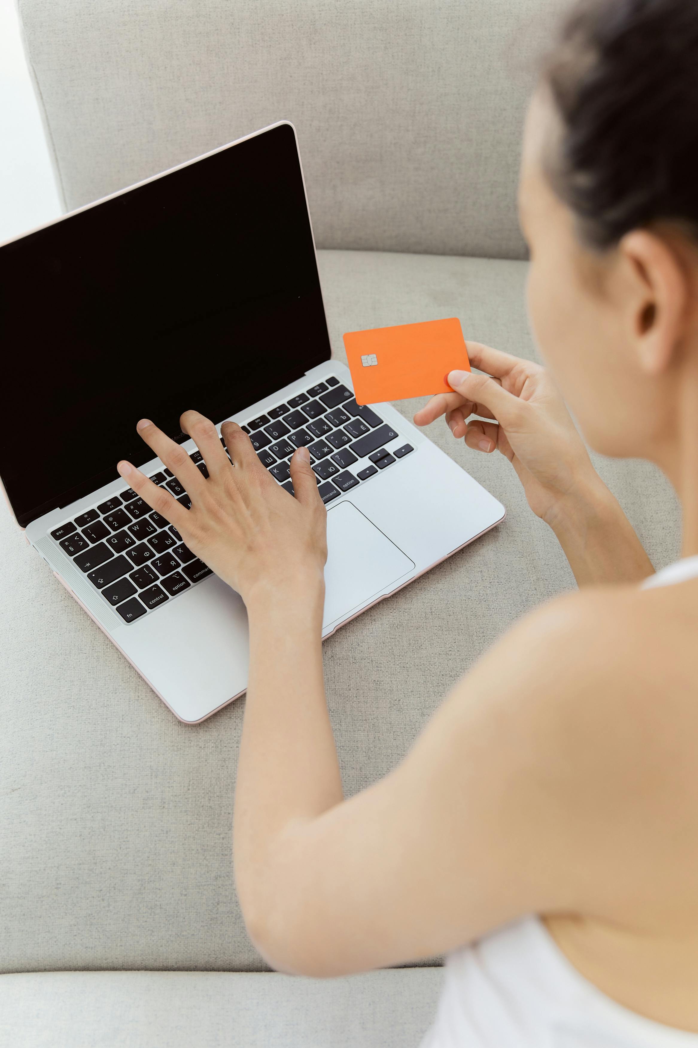 woman holding a bank card and using laptop