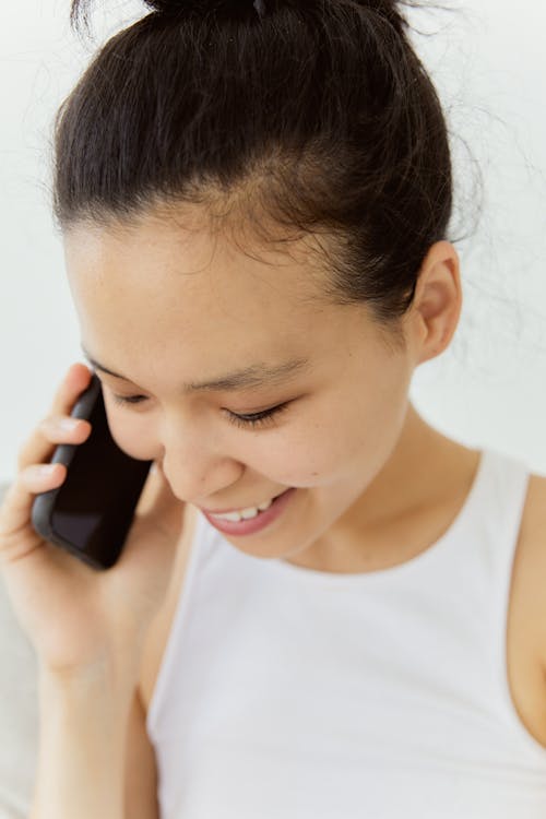 Free A Woman in White Tank Top Talking on Her Cellphone Stock Photo