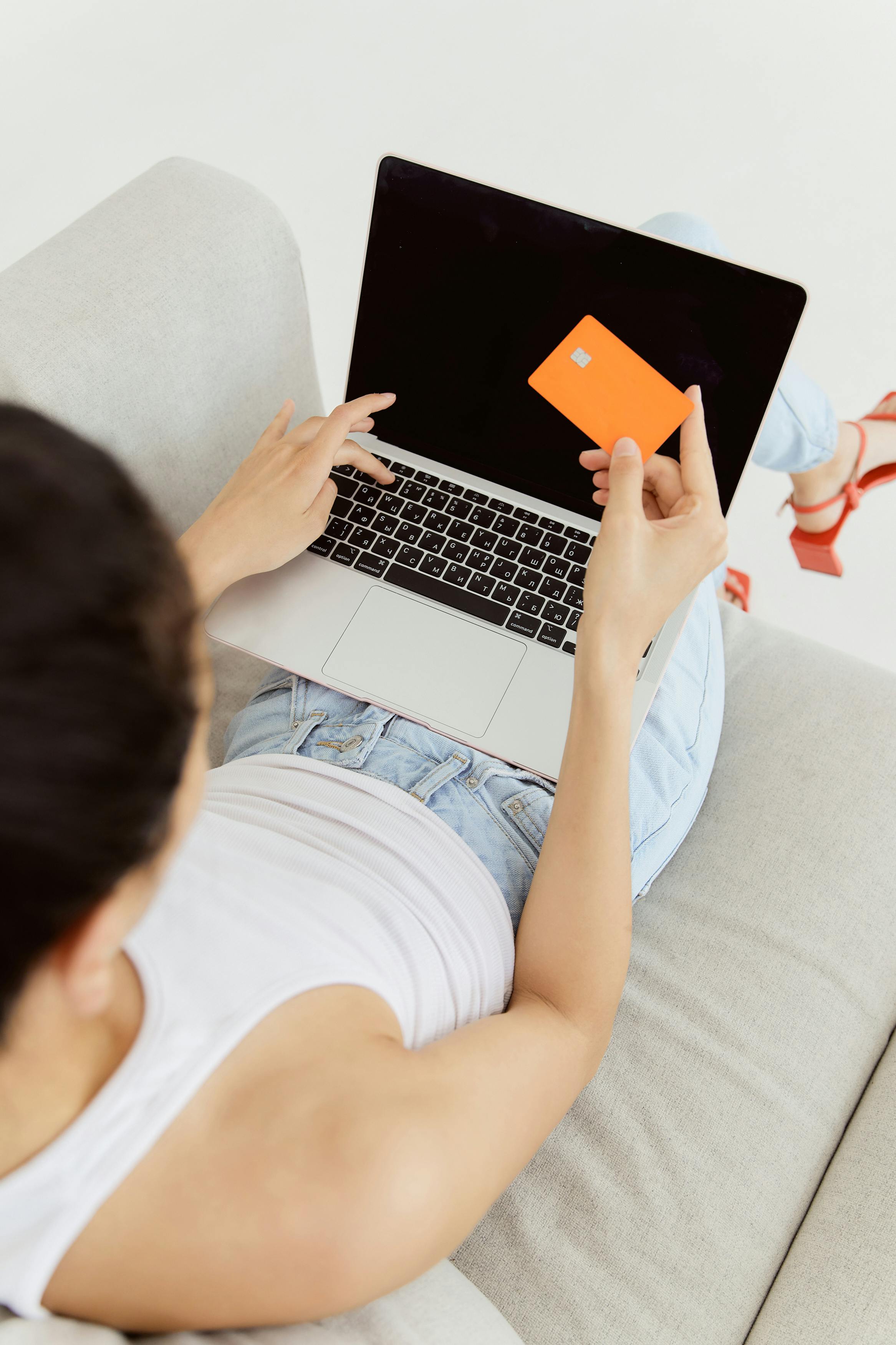 person holding an orange card in front of a laptop