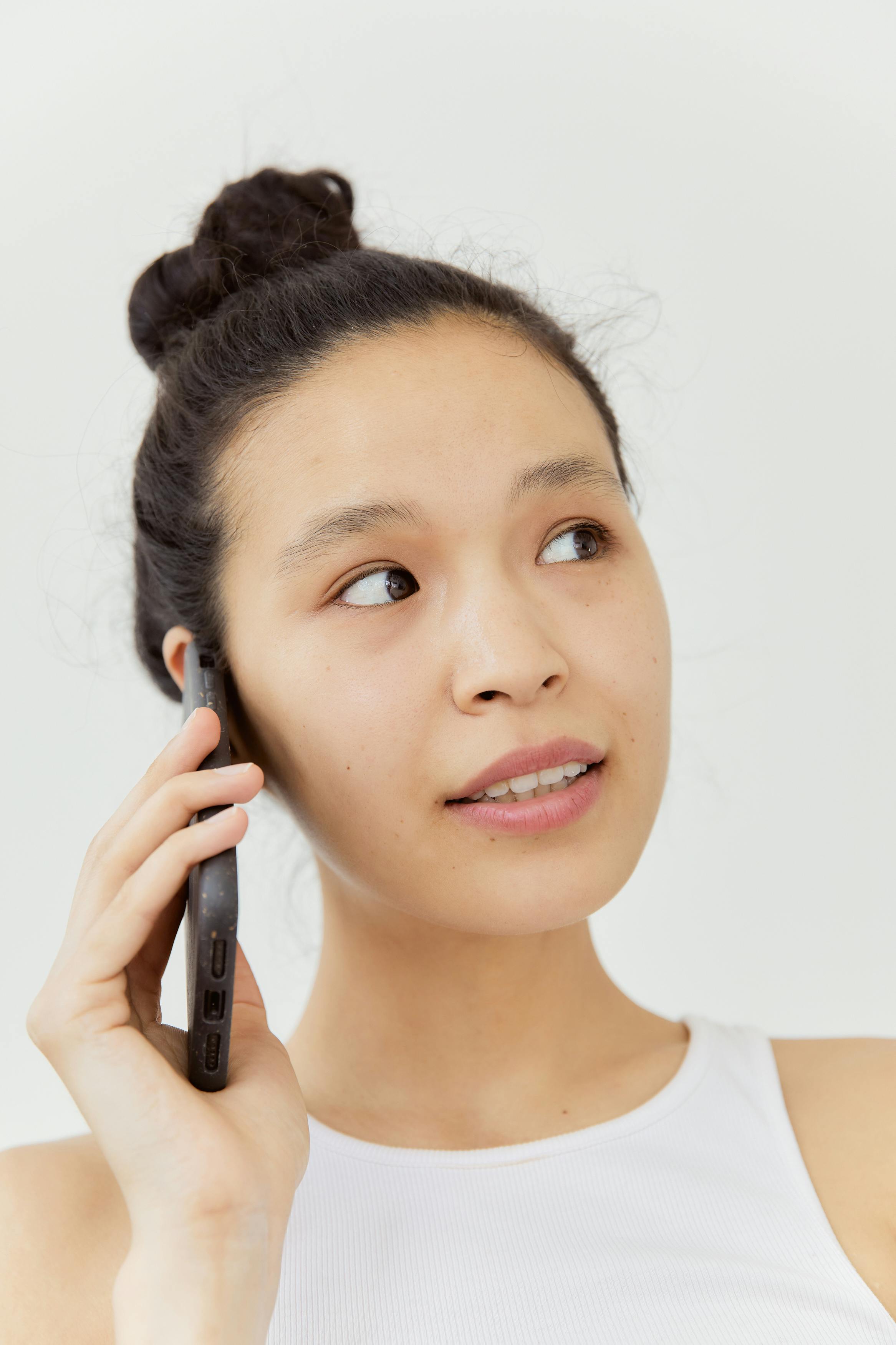 Gratis Mujer Con Camiseta Blanca Usando Un Teléfono Inteligente Negro Foto de stock