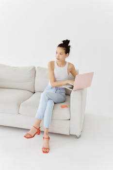 Woman sitting cross-legged on couch using laptop for online shopping.