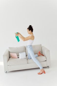 Stylish woman examines newly purchased clothes at home, showcasing modern fashion and online shopping.