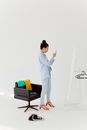 Woman in White Long Sleeve Shirt and White Pants Standing Near Black and Blue Bed