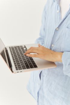 Close-up of a woman typing on a laptop, focusing on hands in a bright setting.