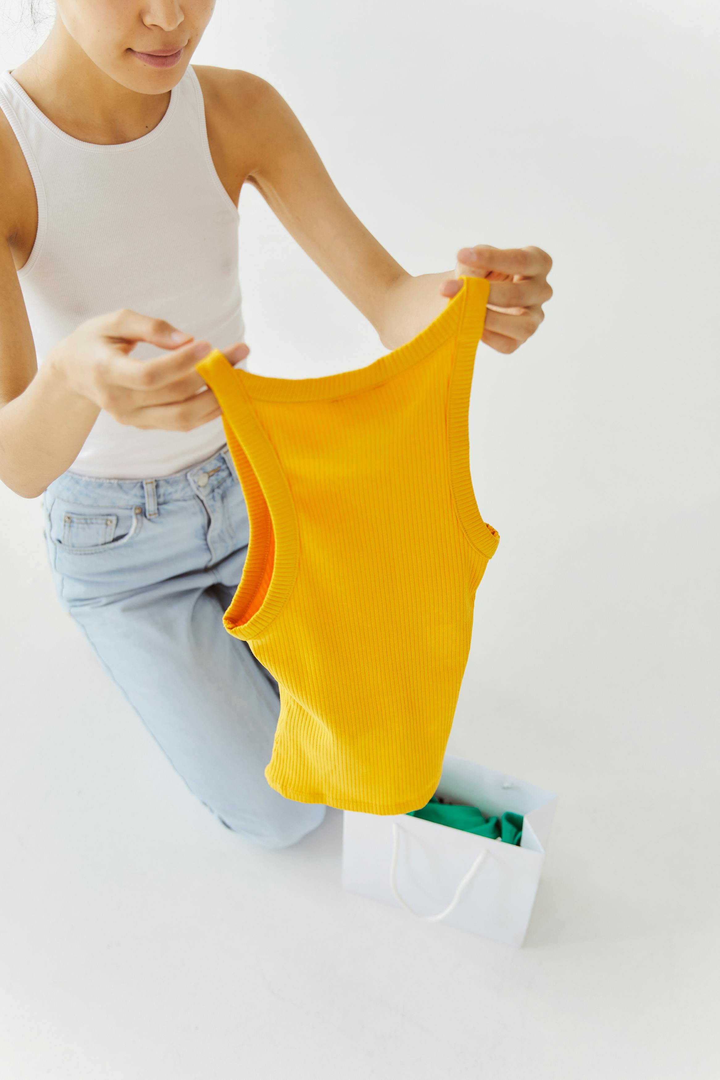 Woman in White Tank Top and Blue Holding a Yellow Tank Top Shirt · Free  Stock Photo