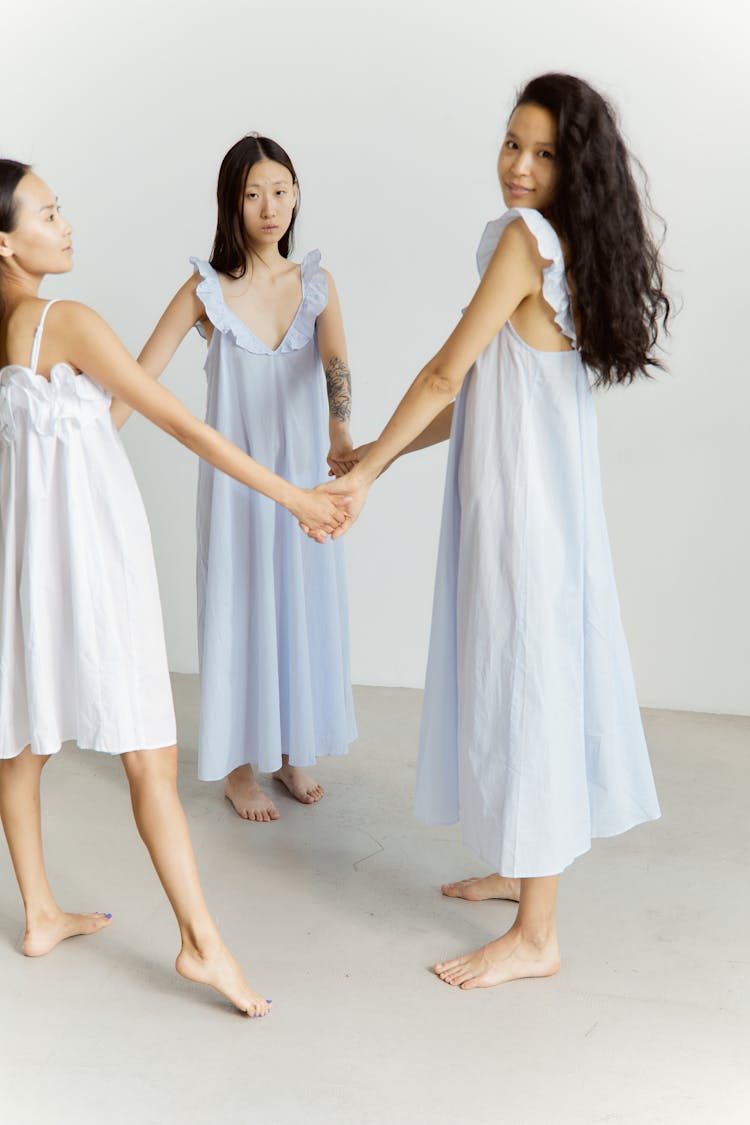 Three Girls In White Dresses Holding Hands Together