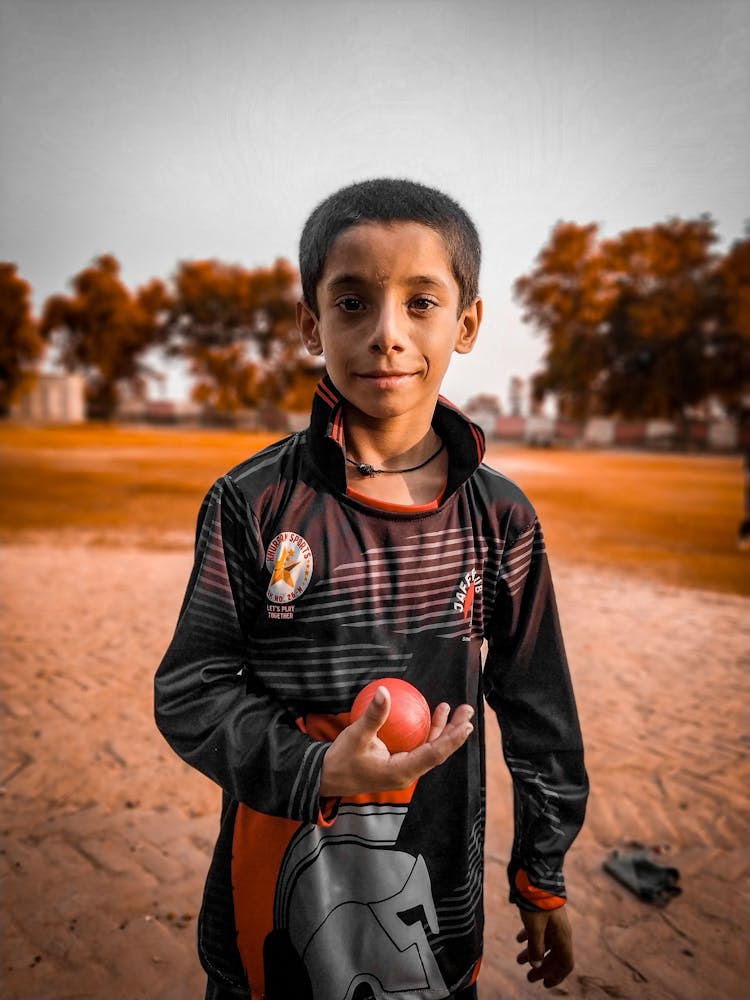 A Portrait Of A Boy Holding A Ball