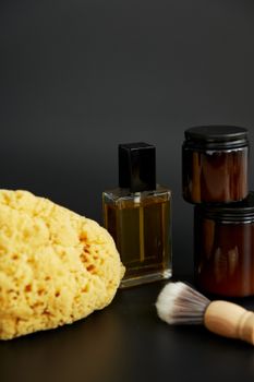 A stylish arrangement of bath products including oil, jars, sponge, and shaving brush.