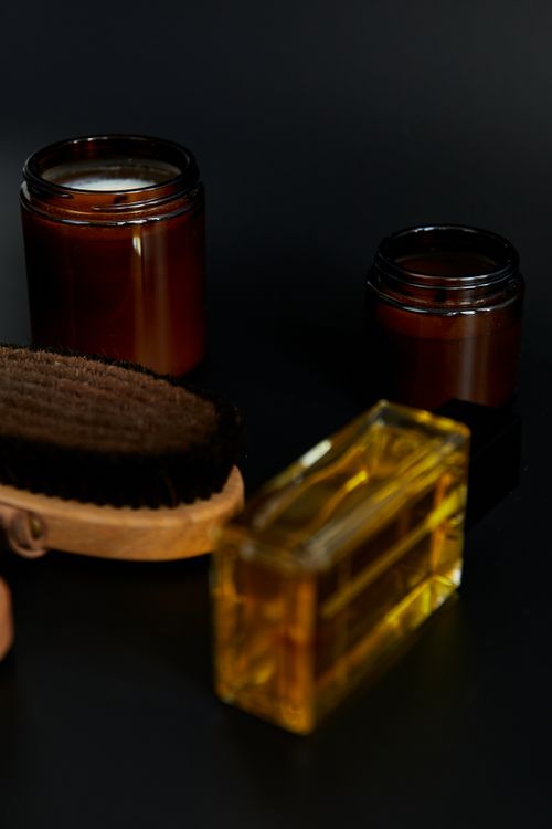Free Stylish spa essentials including amber bottles and grooming brush on a dark surface. Stock Photo