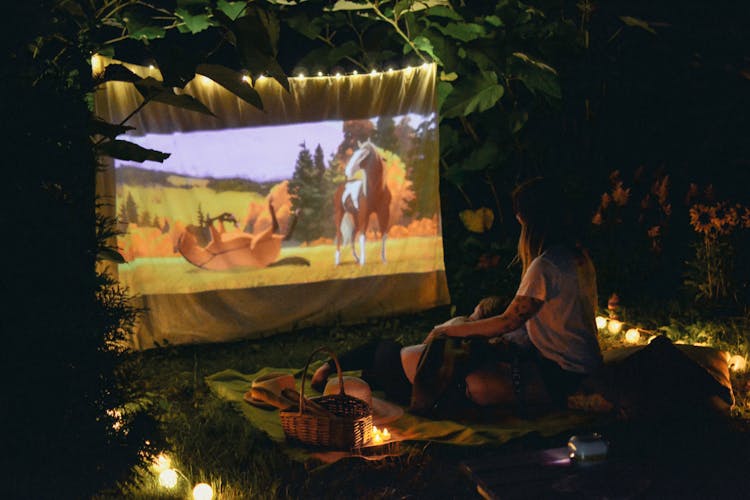 A Couple Watching A Movie At A Picnic Date