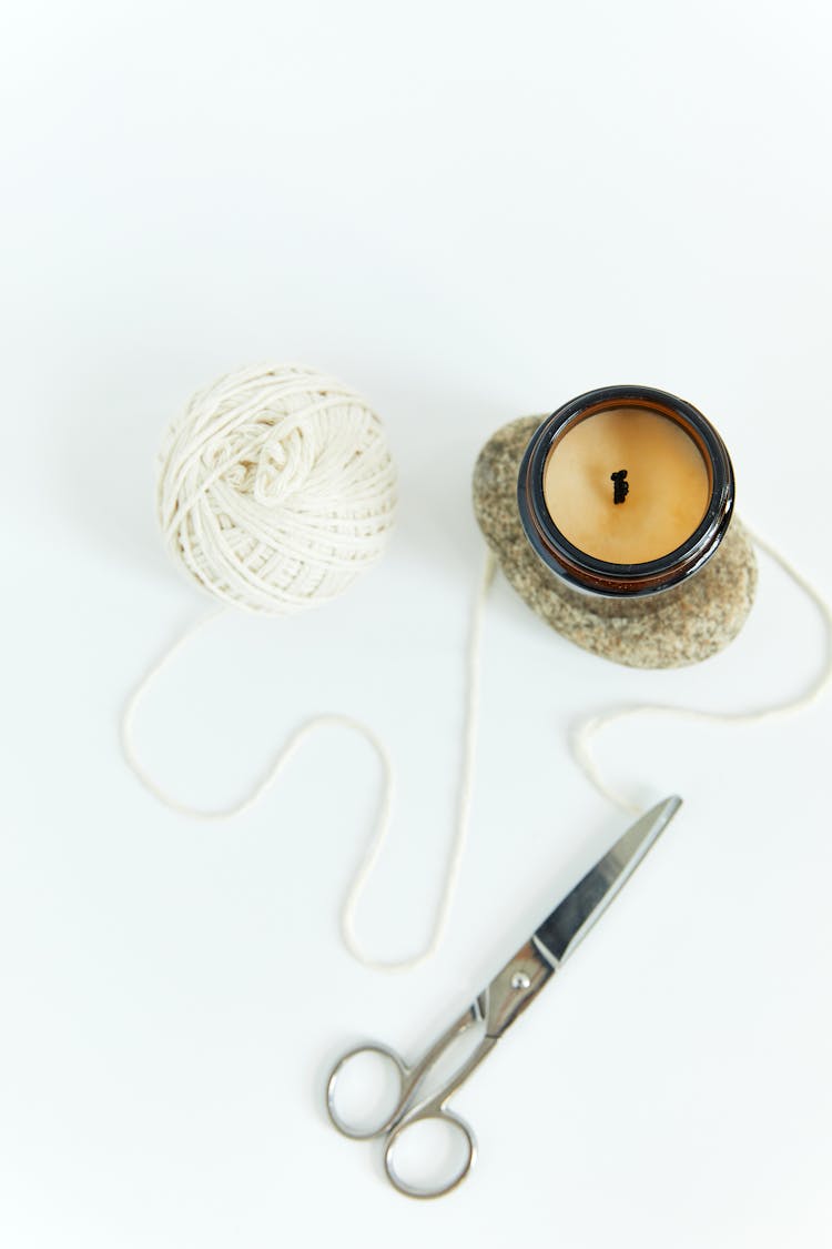 A Thread And Scissor Beside A Candle