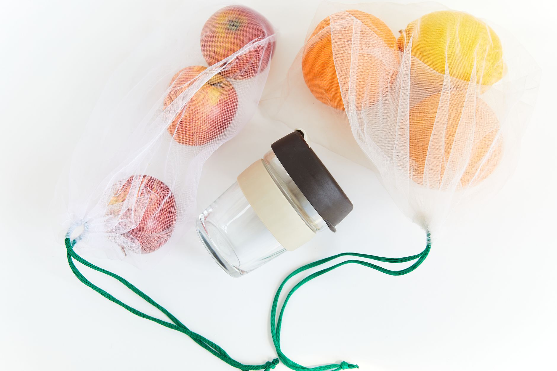 Sustainable lifestyle with reusable mesh bags and a jar on a white background.