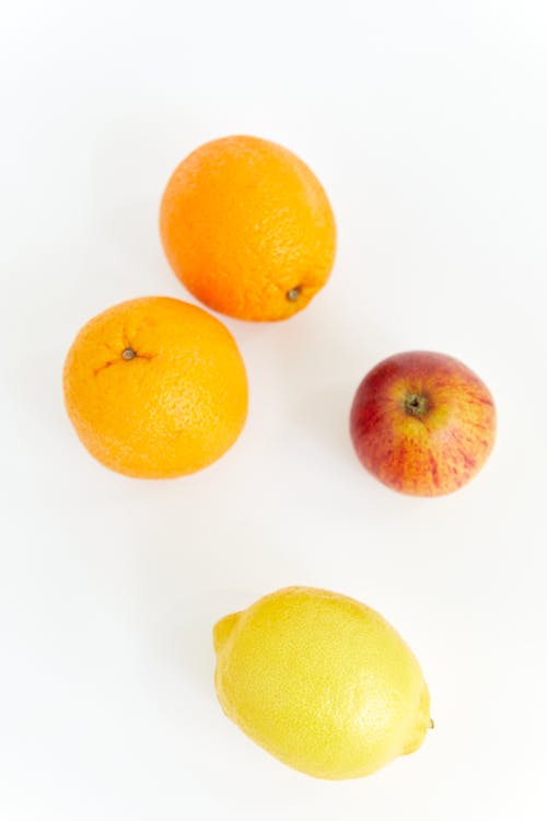 Citrus Fruits and a Apple on White Surface