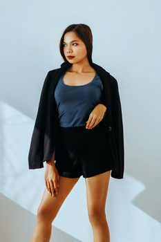 Stylish woman posing indoors in a black blazer and shorts, exuding confidence and elegance.