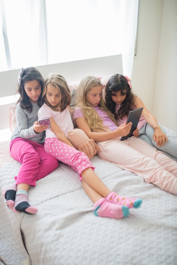 Girls Sitting On Bed Using Mobile Phone