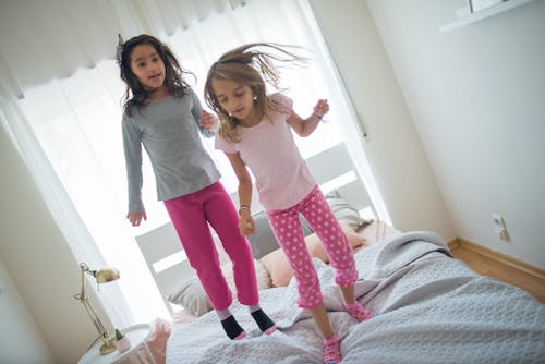 Girl in Gray Long Sleeve Shirt and Pink Pajama Standing Beside Girl in Pink Shirt