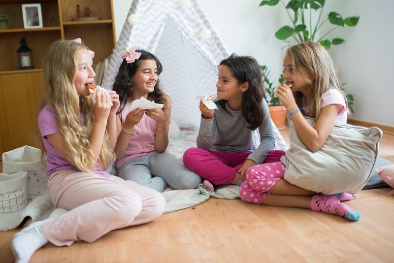Friends enjoying pizza and snacks at a cozy sleepover