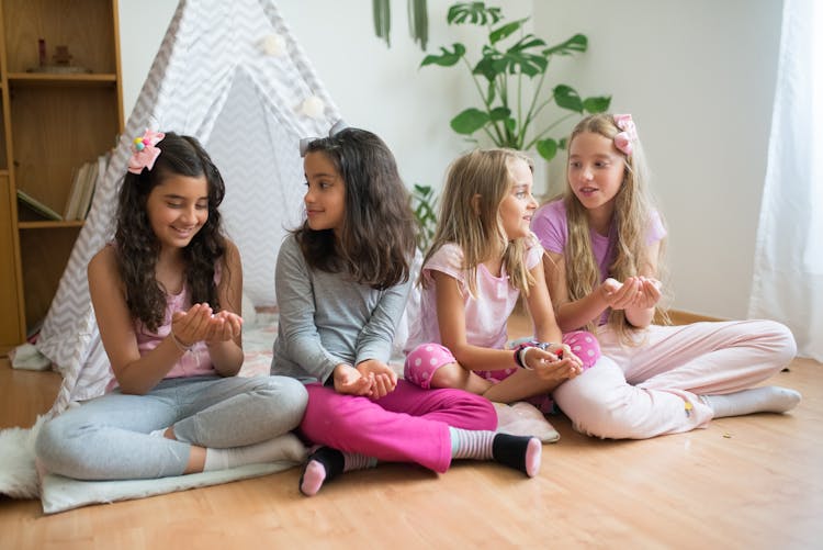 Girls Sitting On Floor Beside Gray Tent