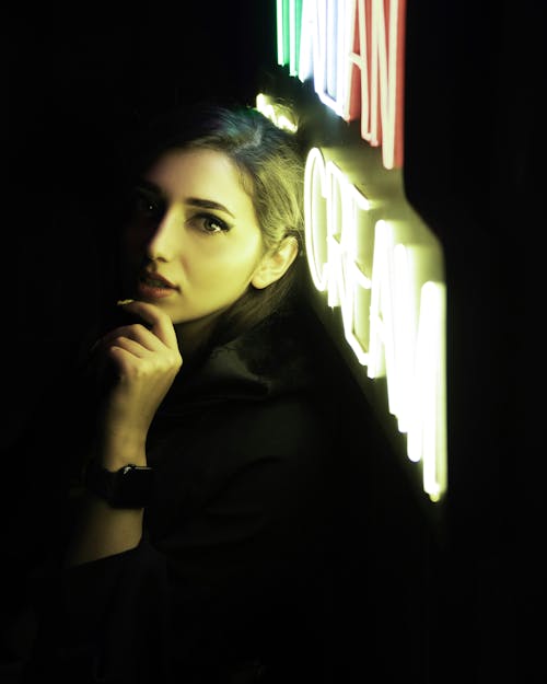 Portrait of a Woman Posing Near a Neon Sign