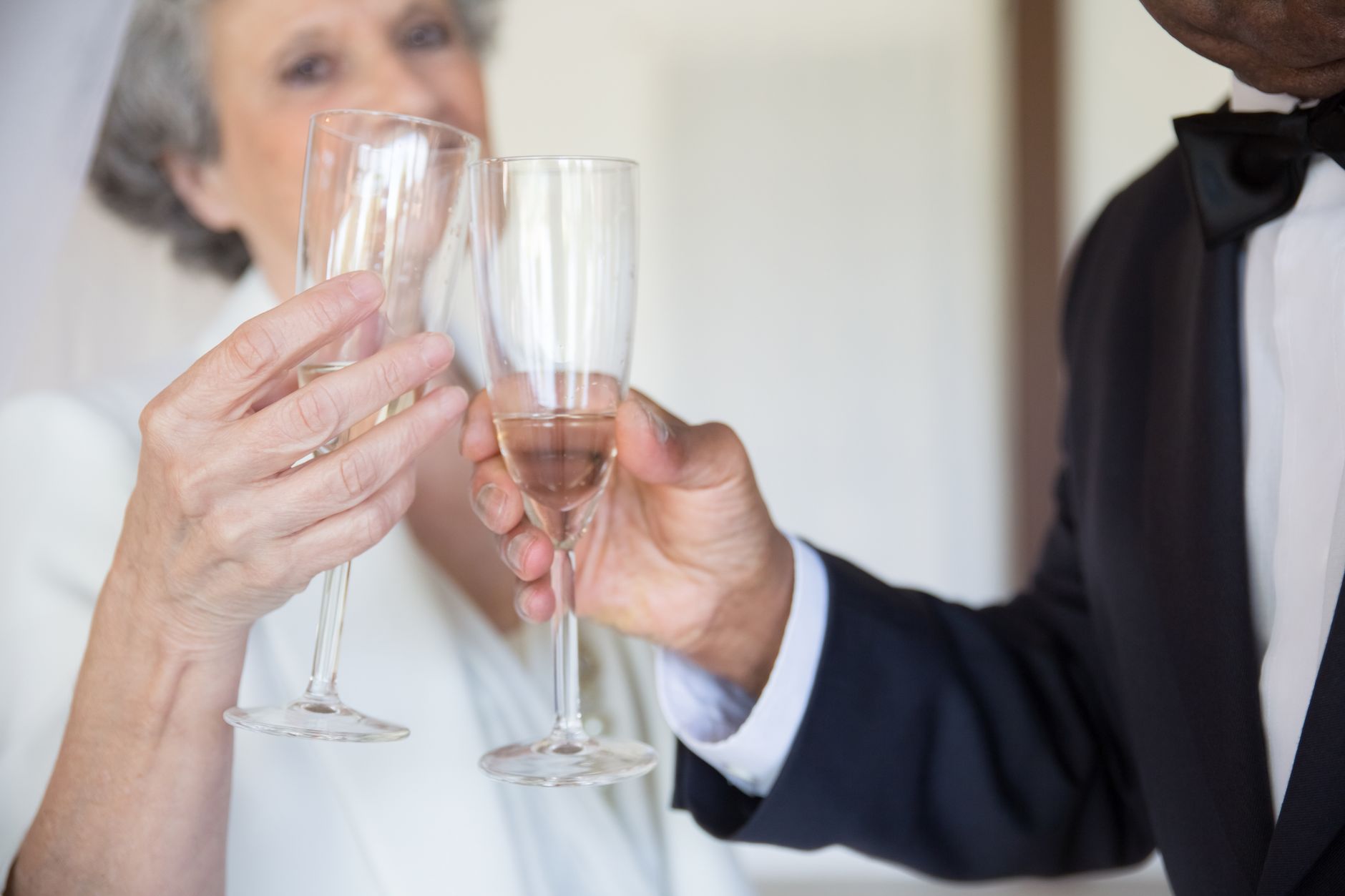 Senior couple in formal attire toasting with champagne glasses, celebrating together.