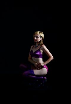 A woman in alluring lingerie poses gracefully in a studio on a black background.