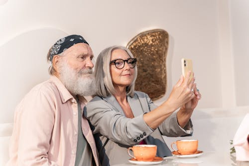Free An Elderly Couple Sitting Beside Each Other while Taking Selfie Using a Cellphone Stock Photo