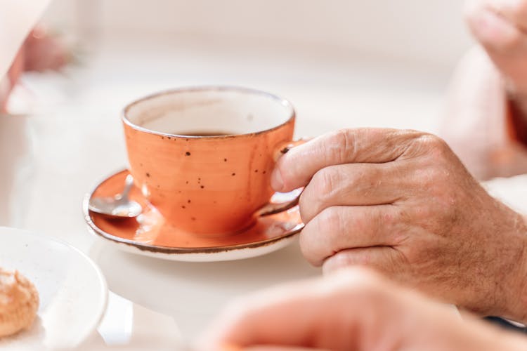 A Hand Getting A Cup Of Coffee On The Table