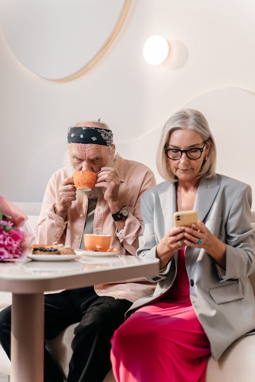 Woman and Man Drinking and Looking at Cellphone