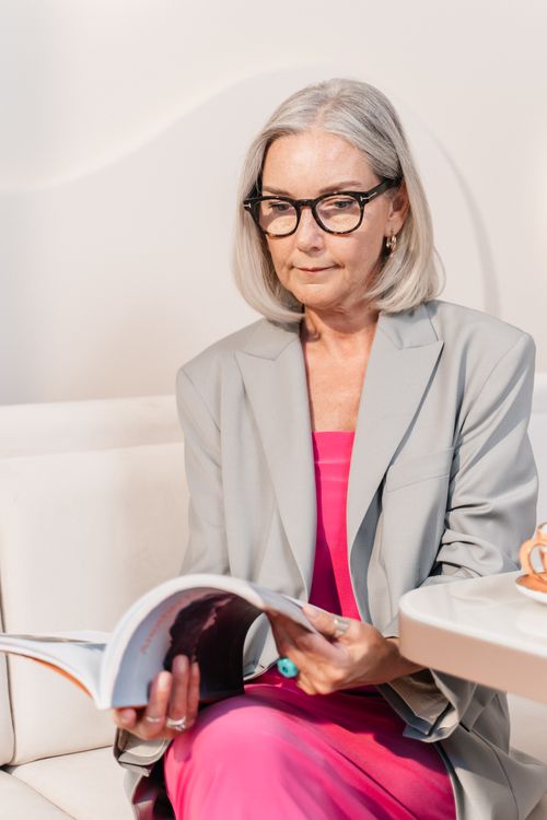 Free Stylish senior adult woman reading a magazine in a contemporary café setting. Stock Photo