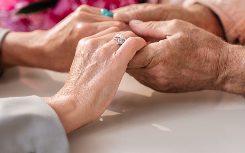 Two pairs of hands held together, flowers soft in the background