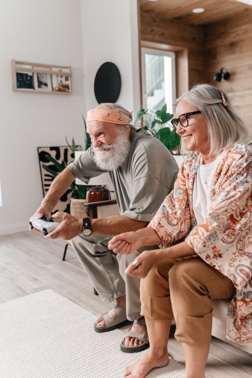 Free Happy senior couple enjoying a video game session at home, capturing joyful bonding moments. Stock Photo