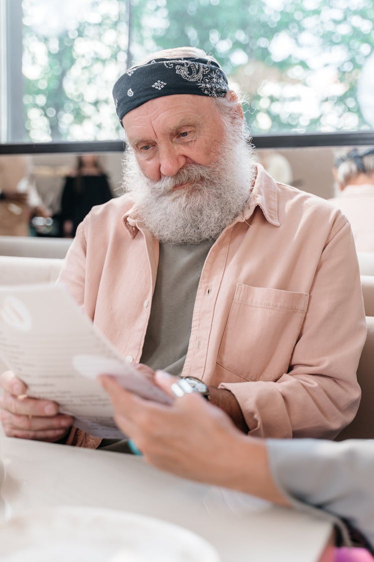 Senior Man With White Beard Looking At A Menu