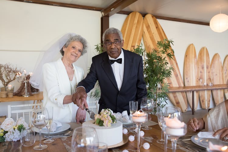 A Couple In Wedding Attires Cutting Wedding Cake