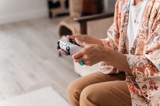A woman wearing a patterned outfit playing video games at home using a controller.