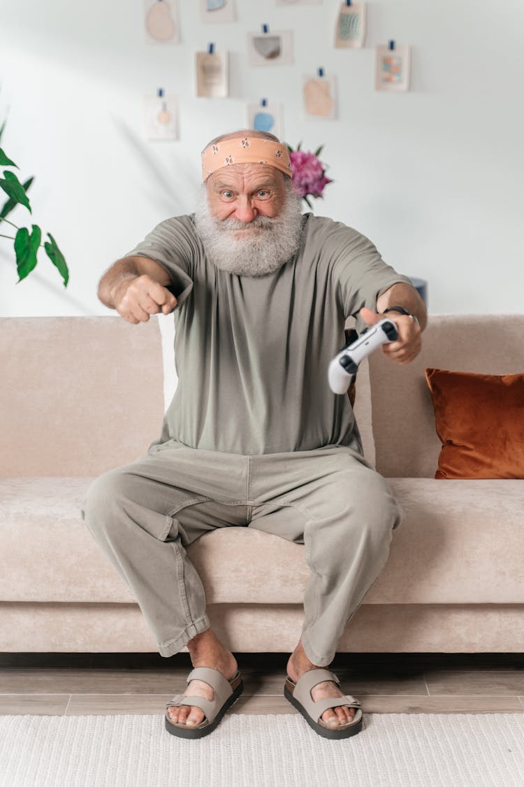 Elderly Man Sitting On Sofa With Game Controler