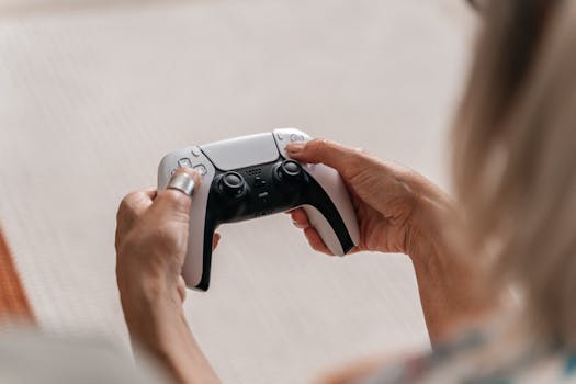 Close-up of adult hands holding a modern game controller, playing video games indoors.