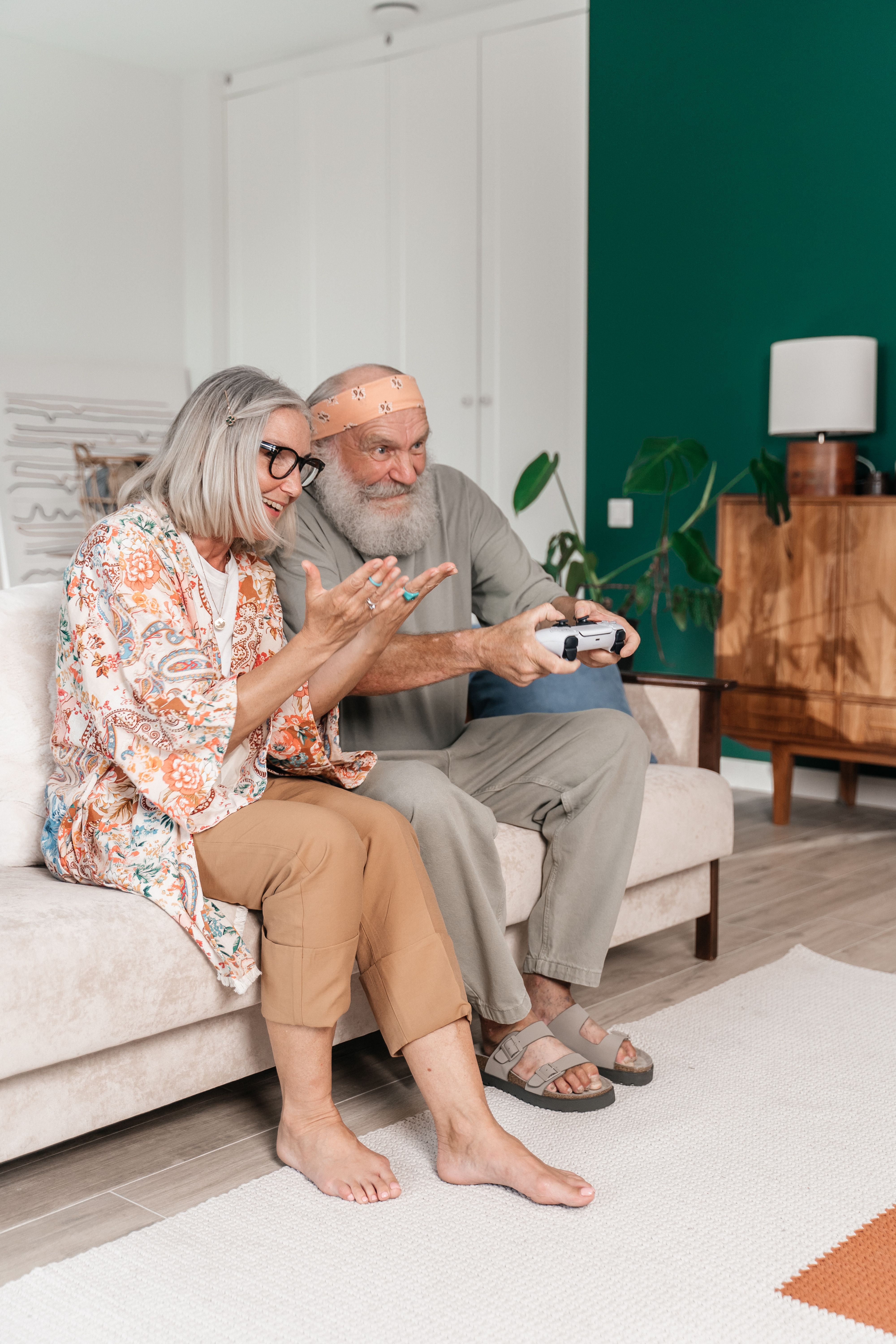 Elderly couple having fun playing video games indoors, showcasing love and togetherness.