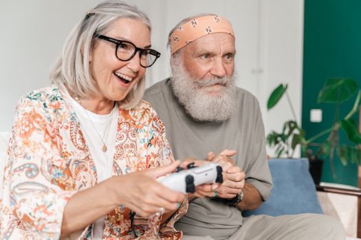 Senior couple happily playing video games indoors, promoting active lifestyles.
