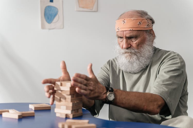 Man In Gray T-shirt Wearing Building Jenga Blocks 